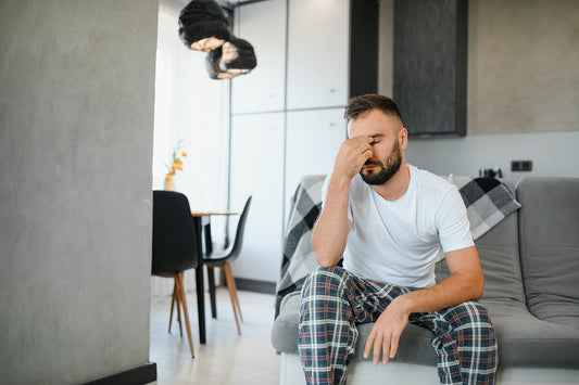 man sitting on couch in living room hand over his face