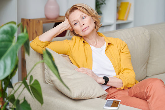 adult woman overthinking sitting on couch in living room wearing colorfull clothing
