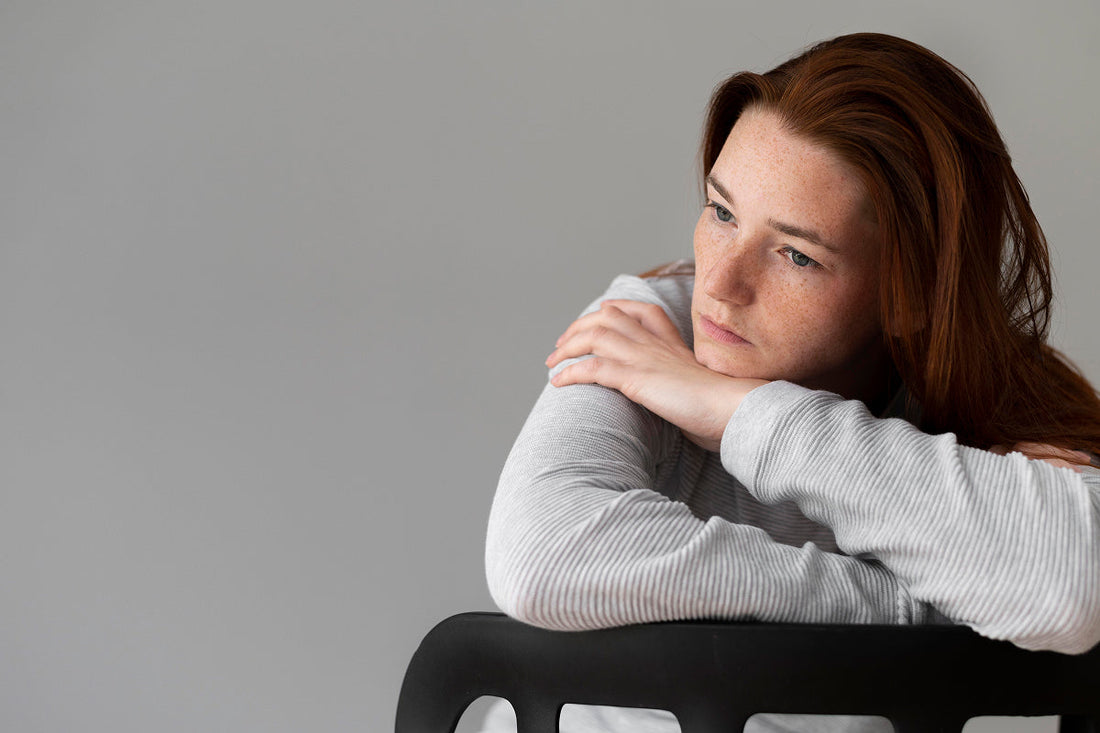 sad looking young woman sitting backwards on a chair leaning