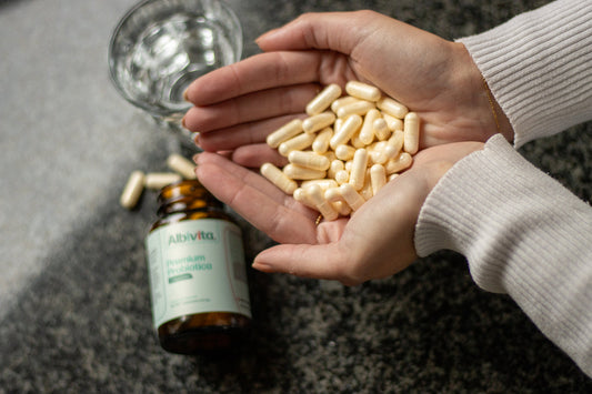 hands together filled with probiotica capsules, jar and glass water on the background