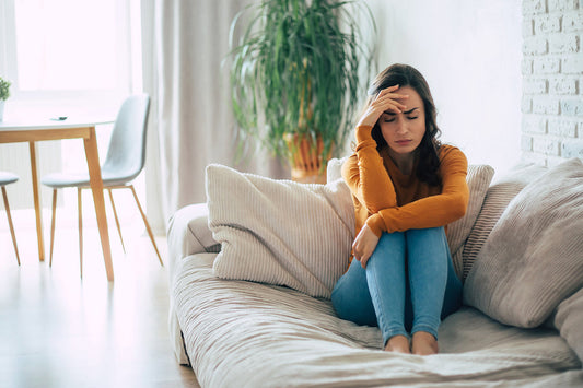 young woman sitting on sofa overthinking