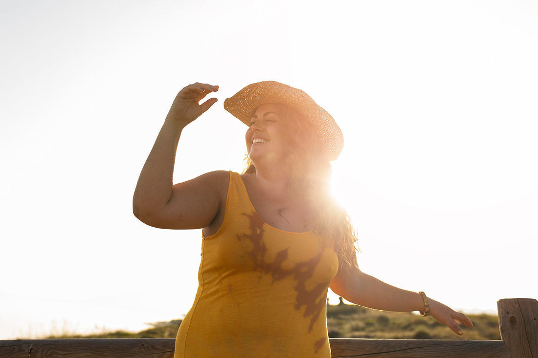 woman with hat on dancing in the sun, yellow dress