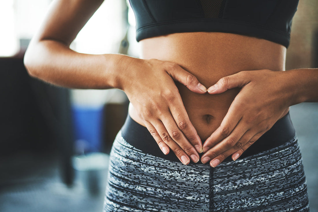 woman in sport clothing holding hands in front of belly in shape of heart
