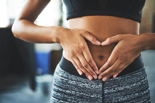 woman in sport clothing holding hands in front of belly in shape of heart