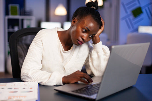 woman looking tired sitting behind desk with laptop