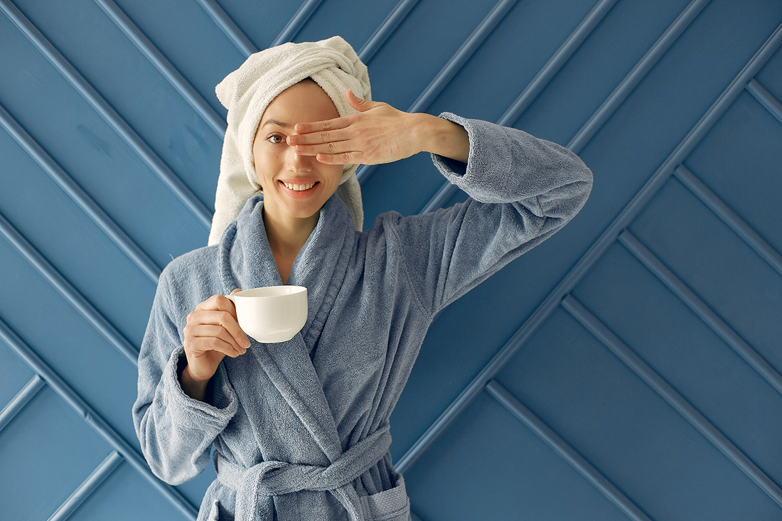 woman holding a cup of coffee in robe and a towel on her head