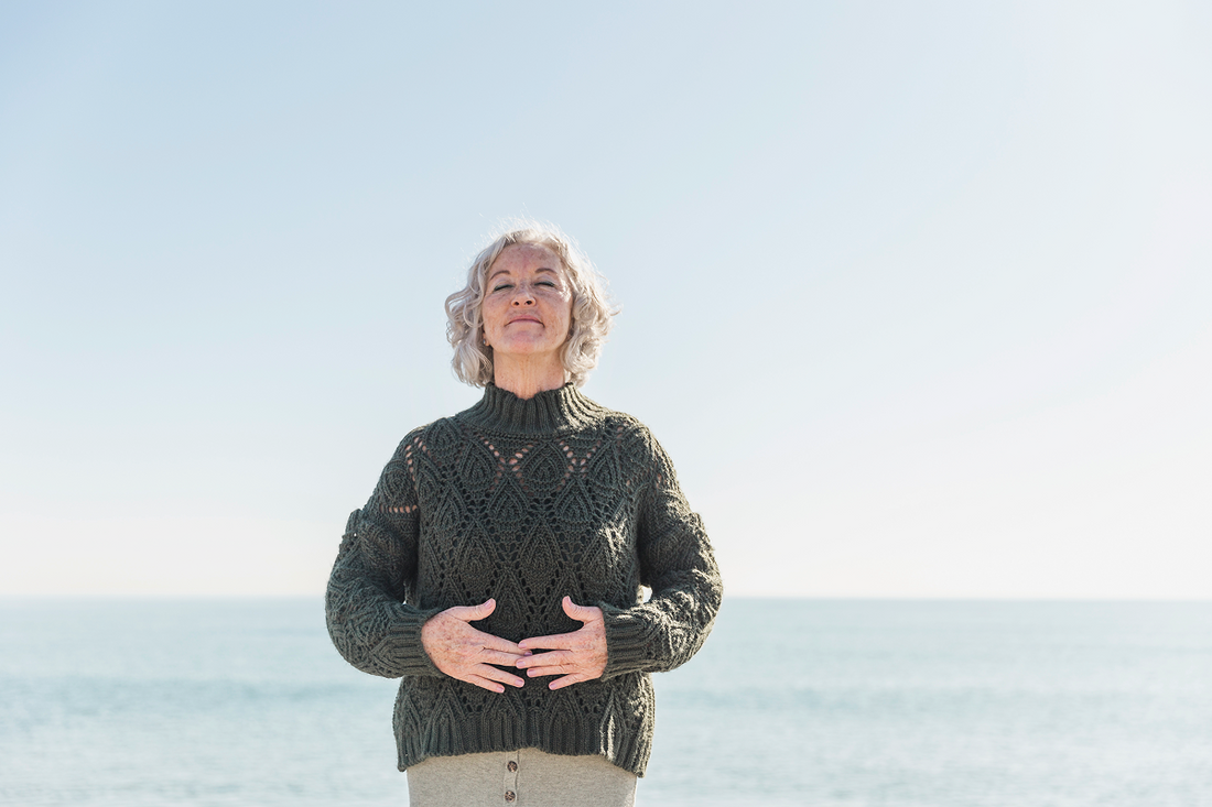 blonde woman holding her stomach standing on the beach